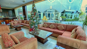 Um lobby com sofás estampados em vermelho, uma mesa de centro de vidro e um pinheiro de Natal.