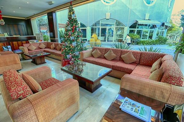 Een hal met rode gestreepte banken, een glazen bijzettafeltje en een kerstboom.