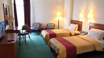 Une chambre d’hôtel avec deux lits, un bureau avec un ordinateur, une chaise et deux lampes.