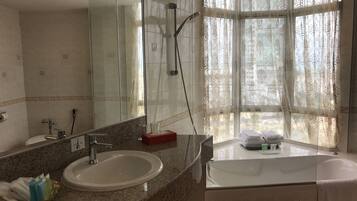 A bathroom with a large mirror, a sink, a shower, and a bathtub.