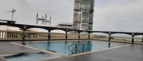 Una piscina con un puente y un edificio alto al fondo.