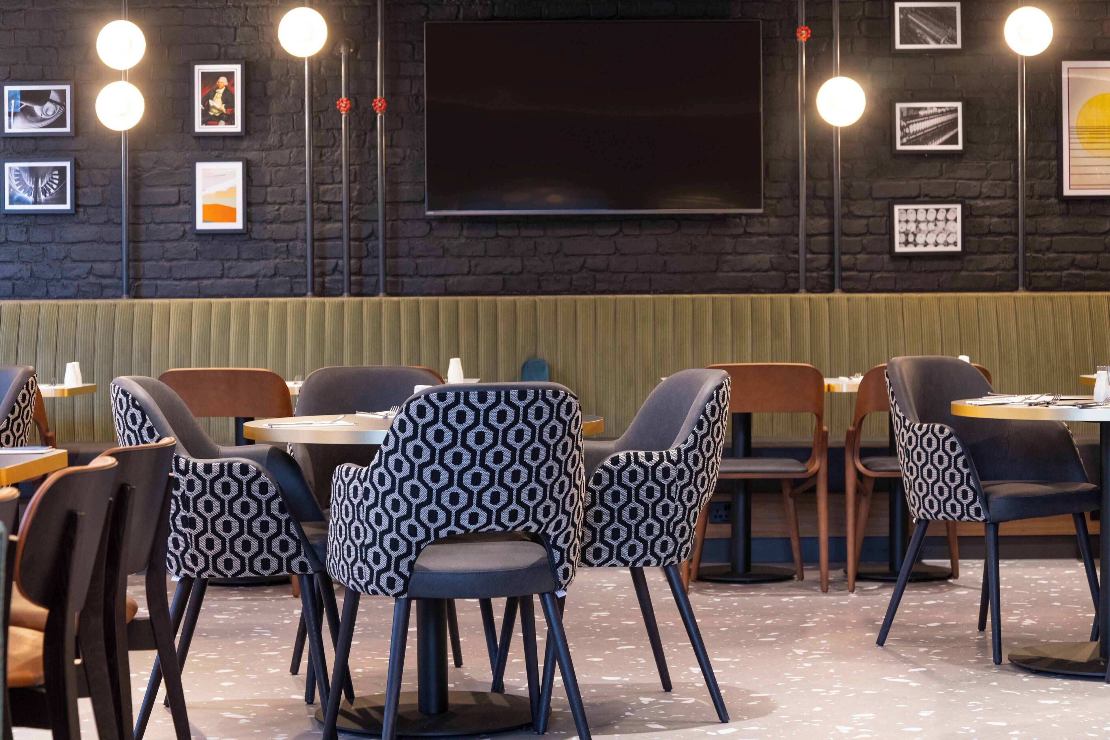 A restaurant with a dark brick wall, framed pictures, and modern lighting.