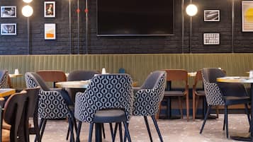A restaurant with a dark brick wall, framed pictures, and modern lighting.