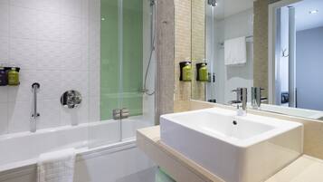 Un baño moderno con ducha de vidrio, una bañera blanca y un lavamanos grande.