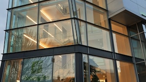 A modern building with multiple floors, large glass windows, and a prominent corner section.