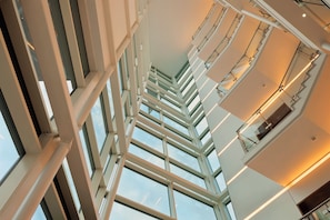 Un interno moderno con soffitto alto e una serie di ampie finestre che lasciano entrare la luce naturale.