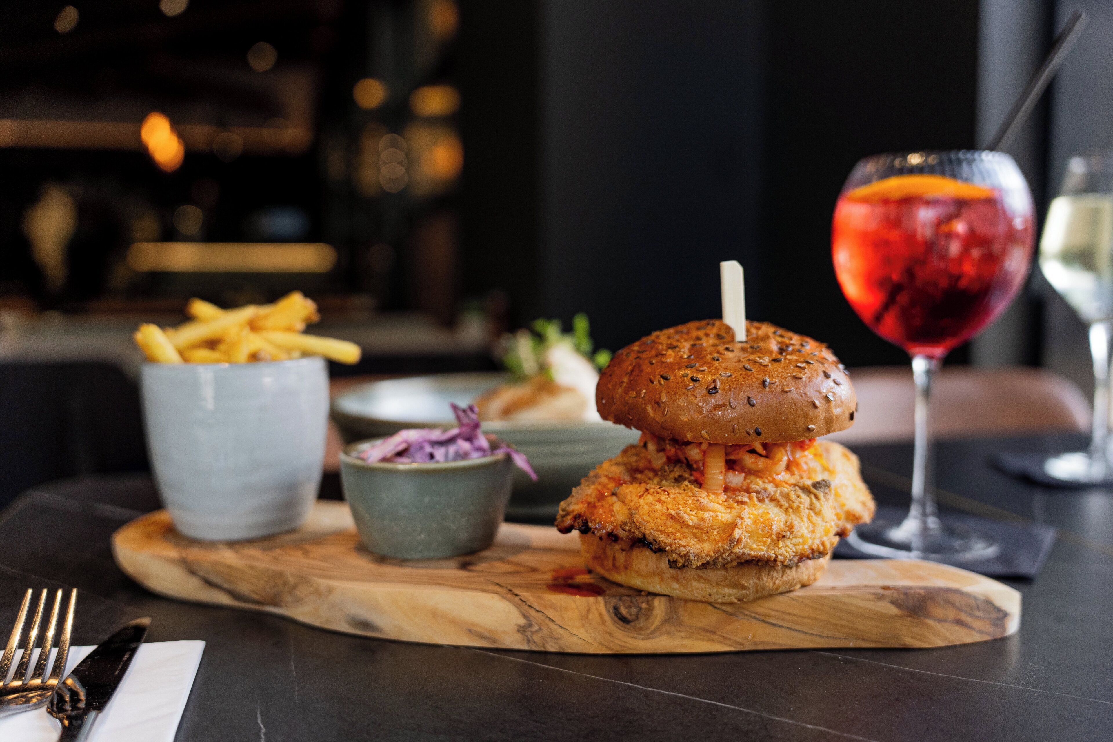 A meal with a sandwich, fries, and a drink on a wooden board.
