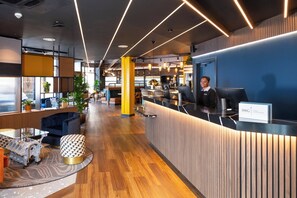 A modern reception area with a counter, seating, and a bar. - Holiday Inn Derby Riverlights by IHG (Derby)
