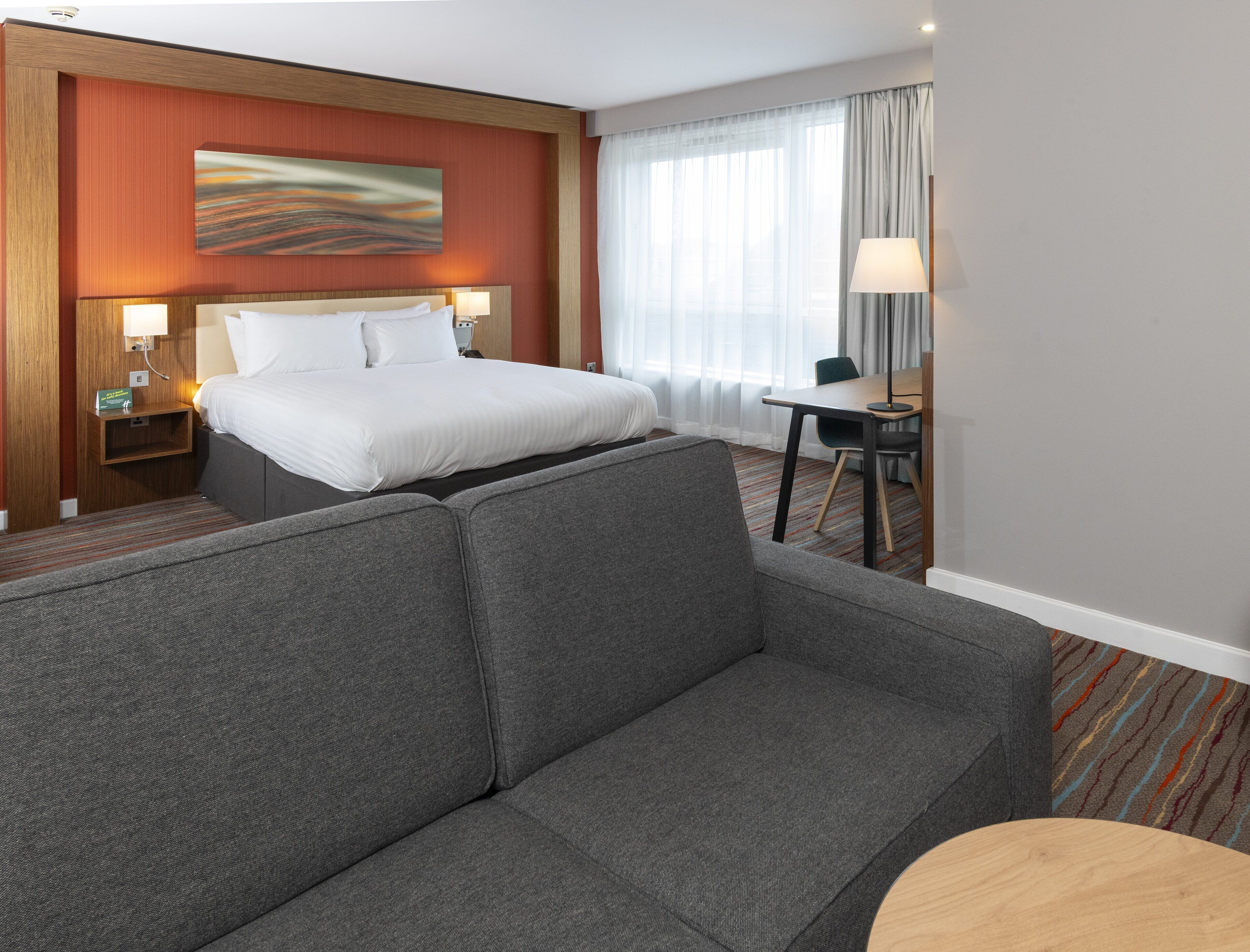 A hotel room with a bed, a sofa, a desk, and a chair.