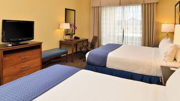 A hotel room with a bed, a desk with a computer, a television, and a chair.