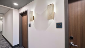 A hotel hallway with a carpeted floor, two doors with numbers 432 and 433, and wall-mounted light fixtures. - Holiday Inn Montgomery Airport South by IHG (Montgomery)