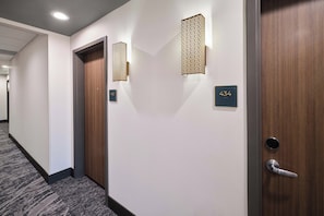 A hotel hallway with a carpeted floor, two doors with numbers 432 and 433, and wall-mounted light fixtures. - Holiday Inn Montgomery Airport South by IHG (Montgomery)
