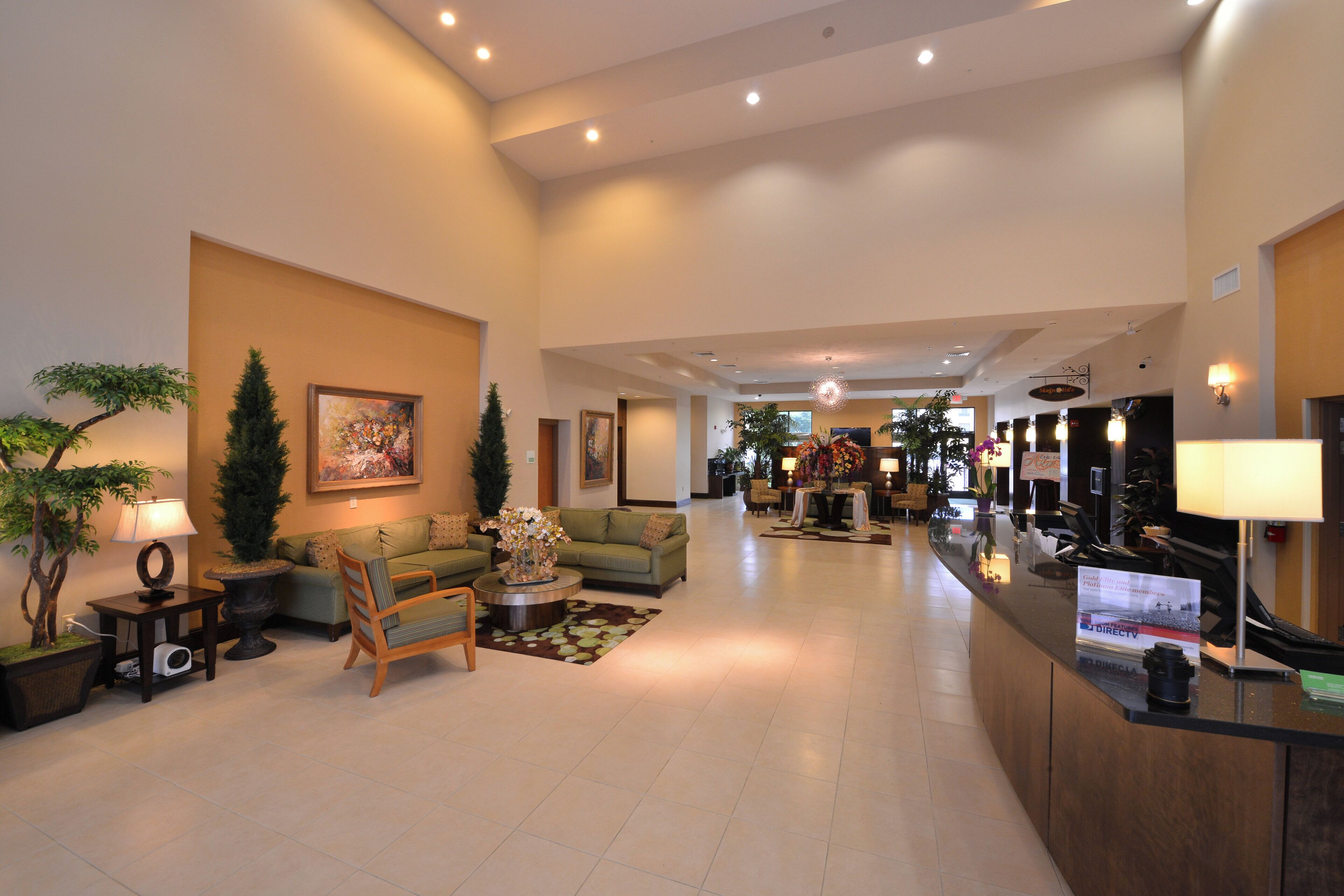 A spacious hotel lobby with a reception desk, seating area, and a large painting on the wall.