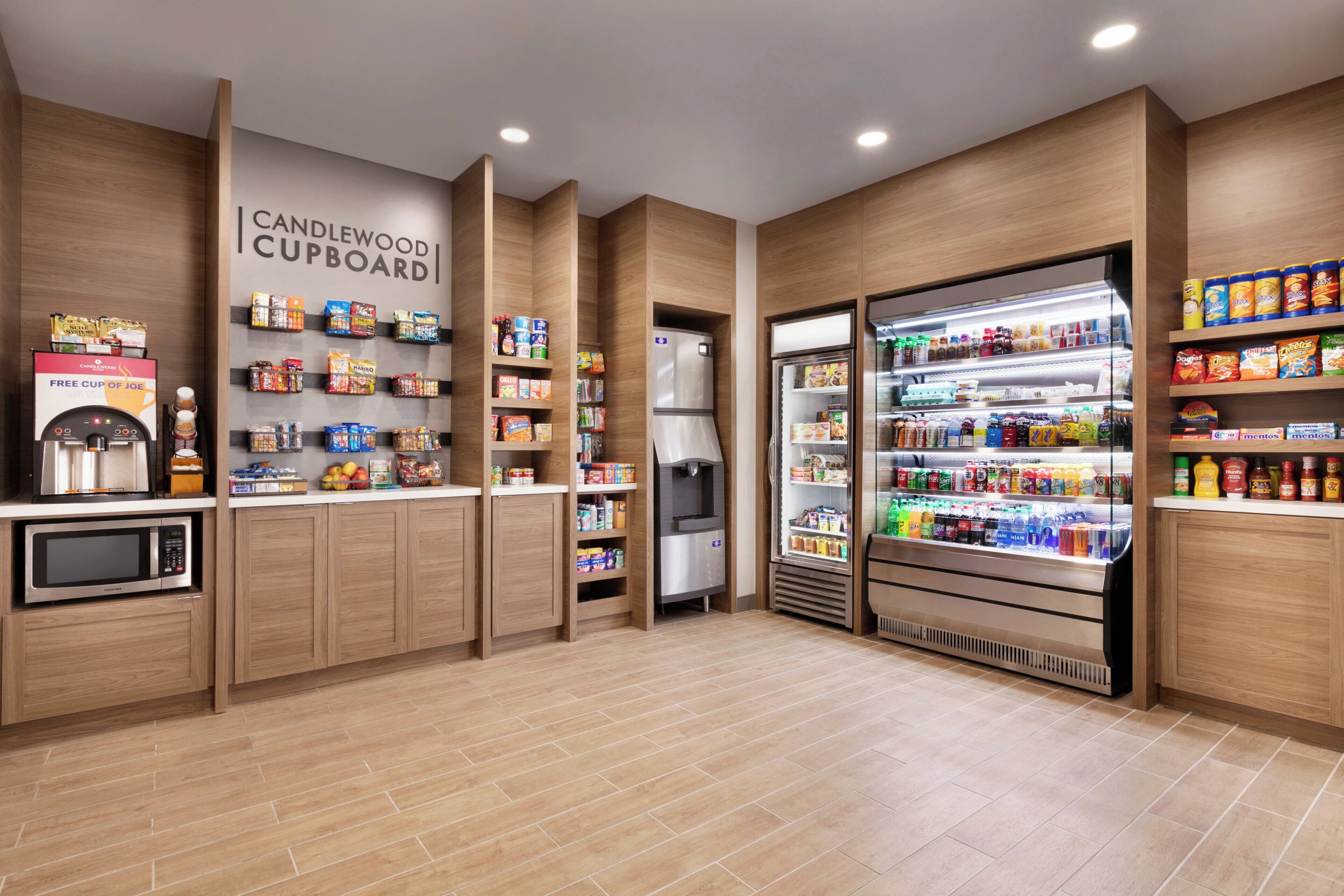 Una kitchenette con microondas, refrigerador y diversos alimentos.