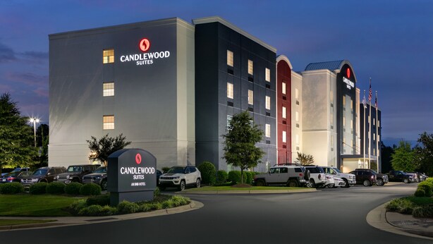 A hotel with a prominent "Candlewood Suites" sign, multiple parking spaces, and a well-lit entrance. - Candlewood Suites Fayetteville Fort Bragg by IHG (Fayetteville)