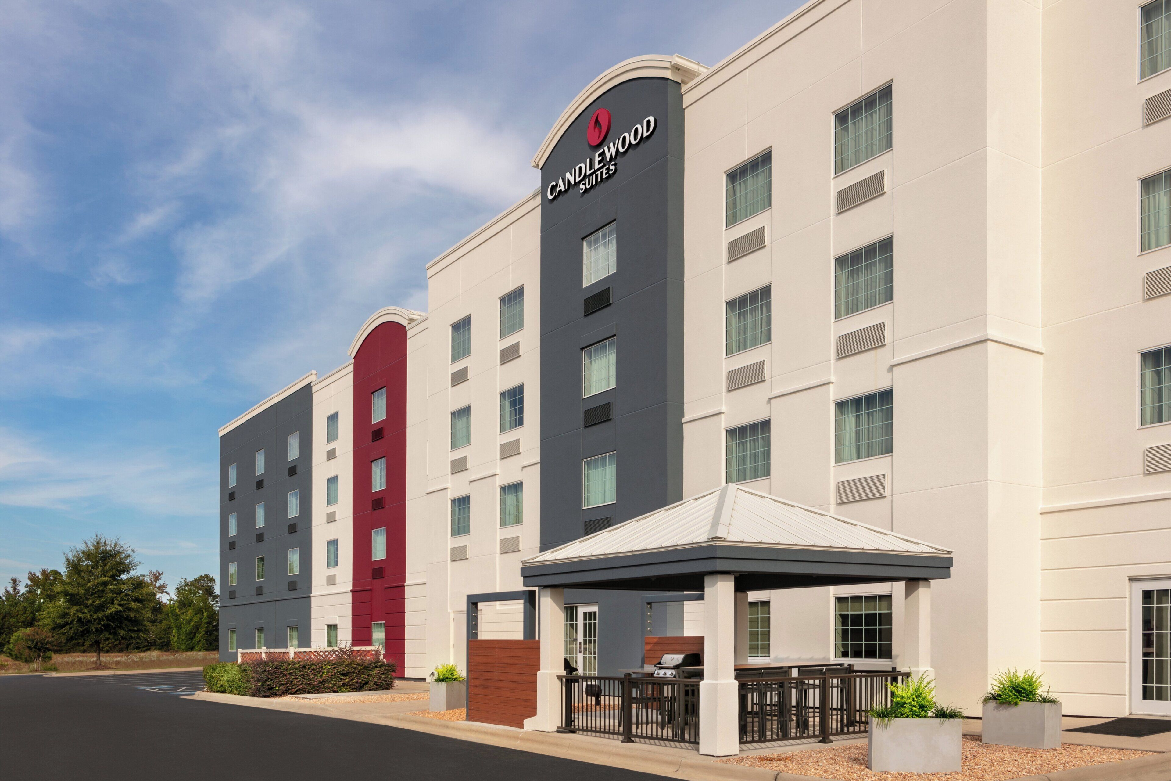 A hotel with a modern facade, multiple windows, and a covered outdoor seating area.