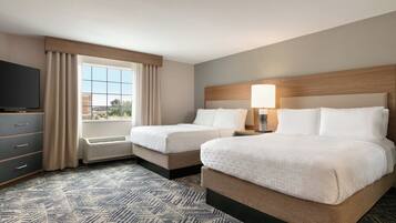 A hotel room with two beds, a TV, a window with curtains, and a patterned carpet.