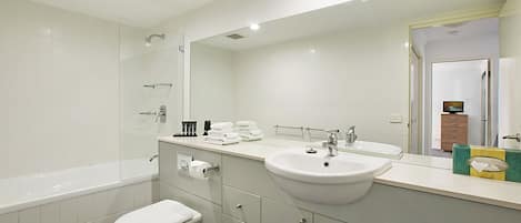 A modern bathroom with a bathtub, toilet, sink, and large mirror.