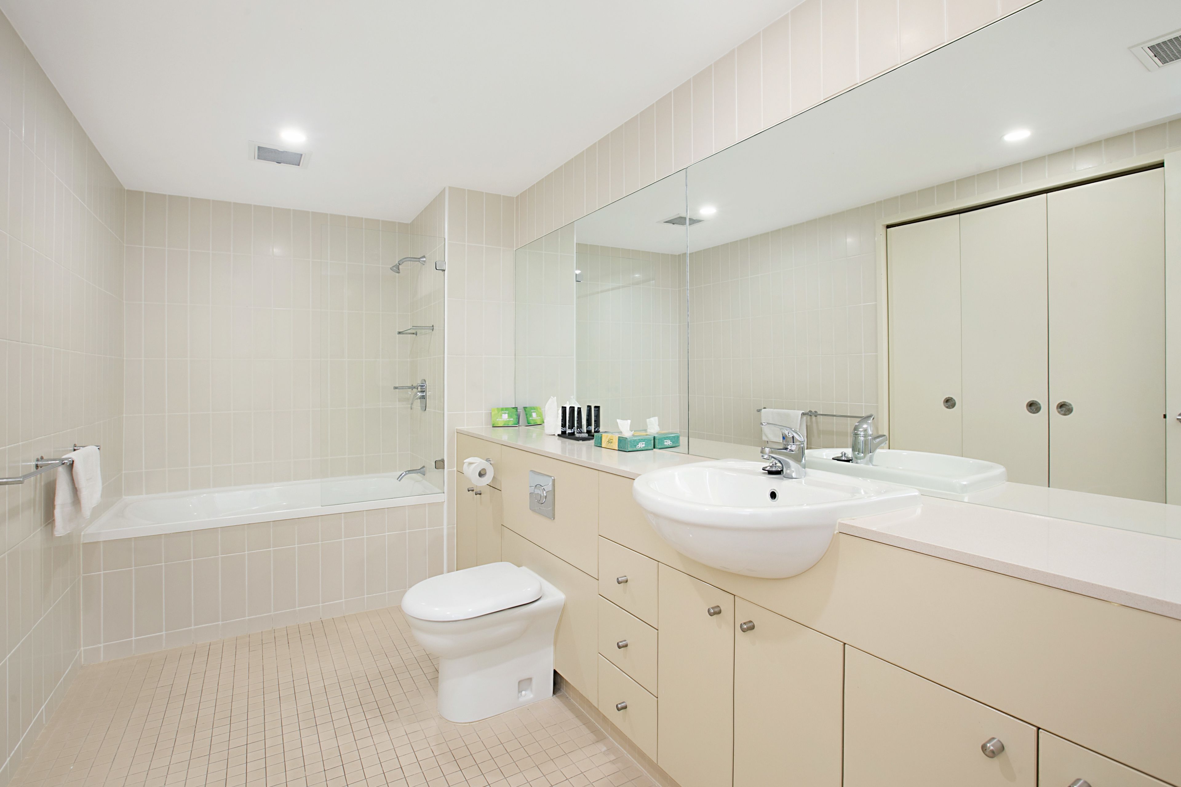 A modern bathroom with a bathtub, toilet, and vanity with a sink and mirror.