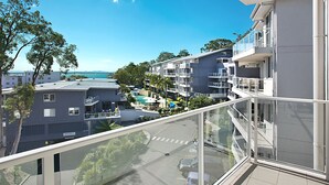 Un moderno edificio de apartamentos con varios balcones y vista a una zona de piscina.