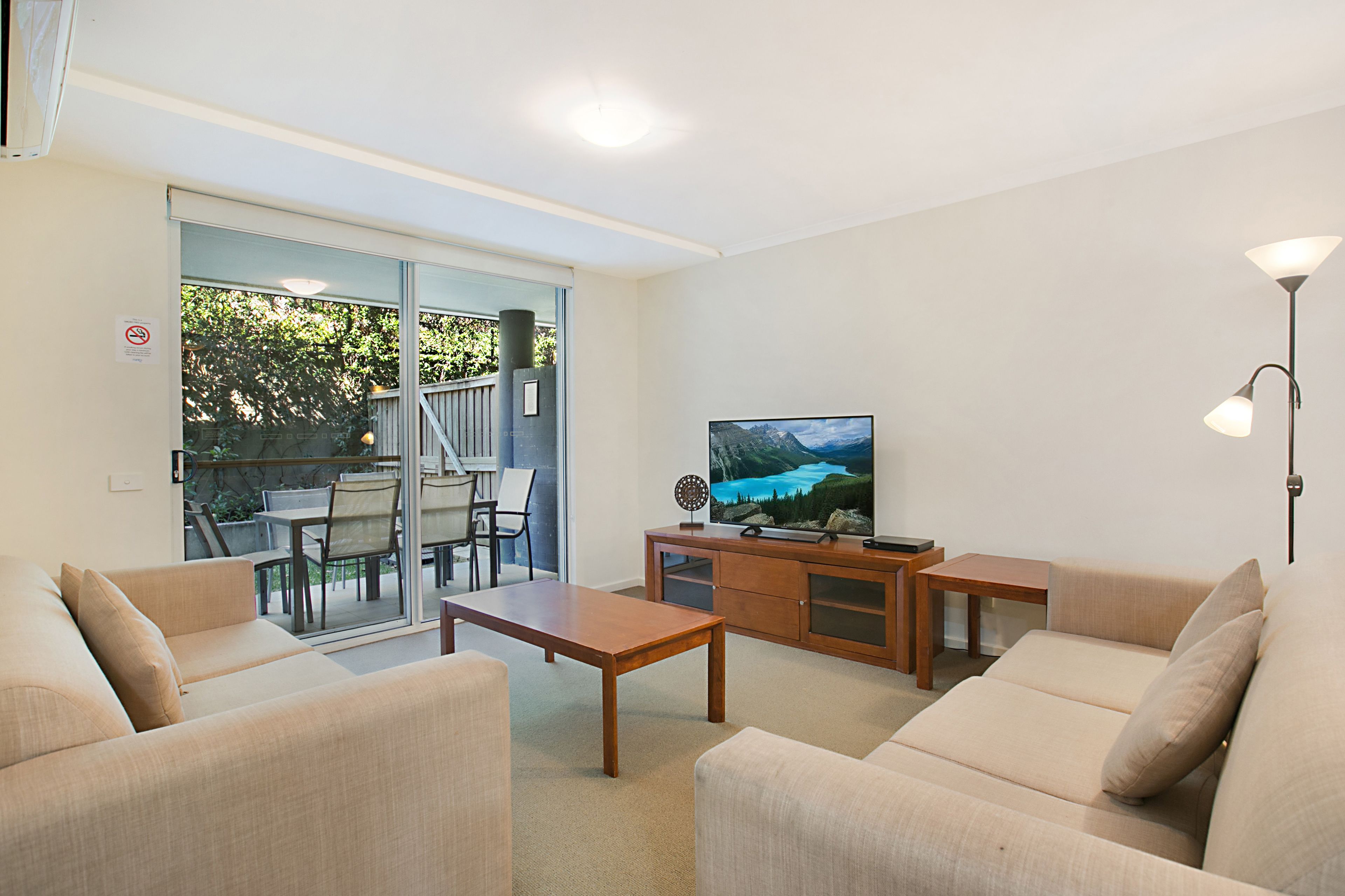 A modern living room with a sofa, a coffee table, a TV, and a dining area with chairs and a table.