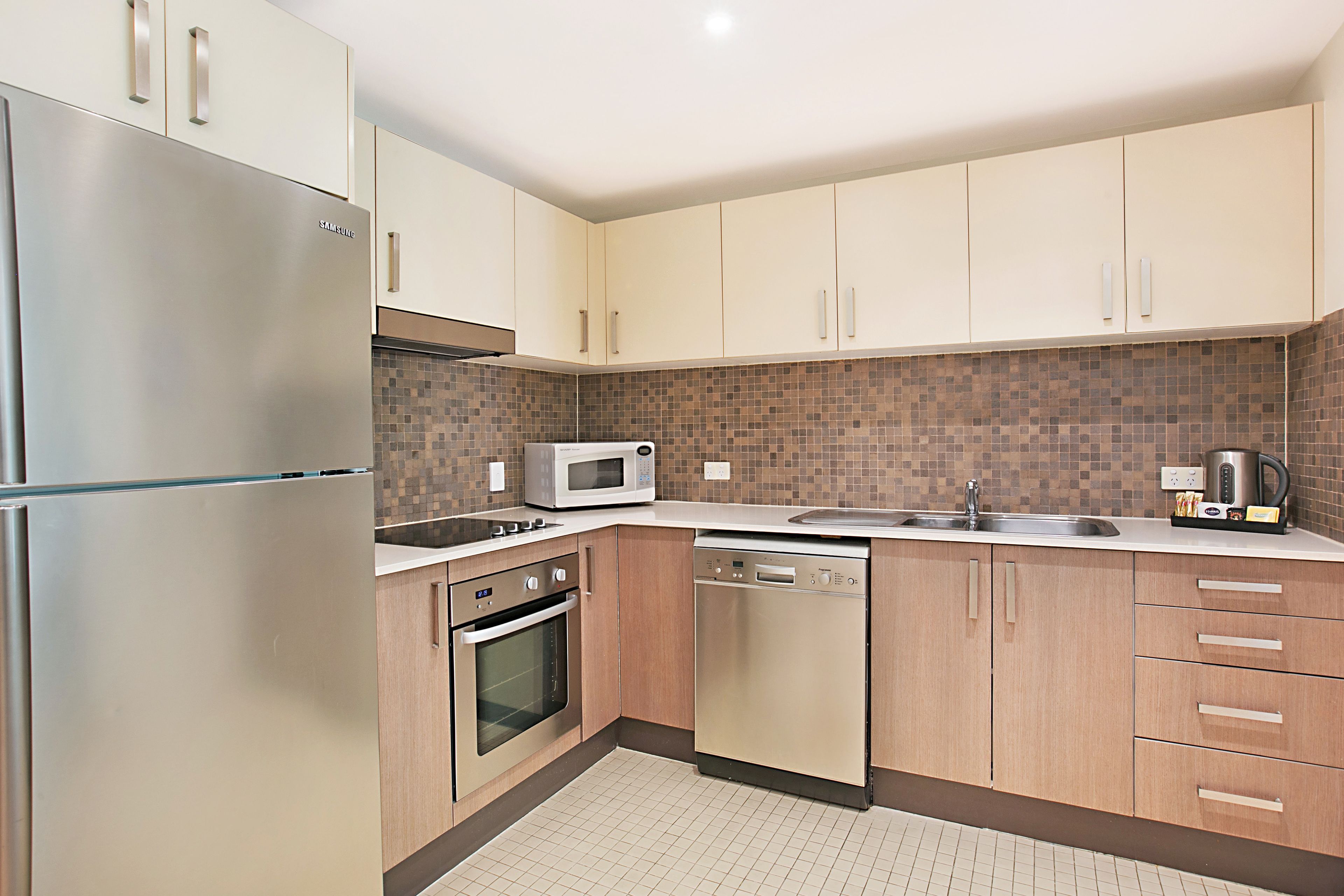 A modern kitchen with stainless steel appliances, wooden cabinets, and a tiled backsplash.