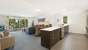 Una cocina moderna con una isla grande, comedor con sillas y un sofá.