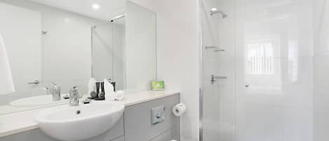 Ein modernes Badezimmer mit Waschbecken, Spiegel und Toilette in Weiß.