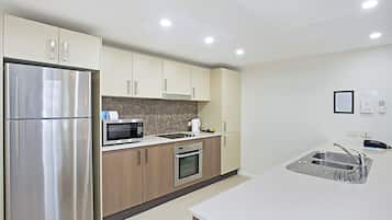 A modern kitchen with stainless steel appliances, wooden cabinets, and a white countertop.