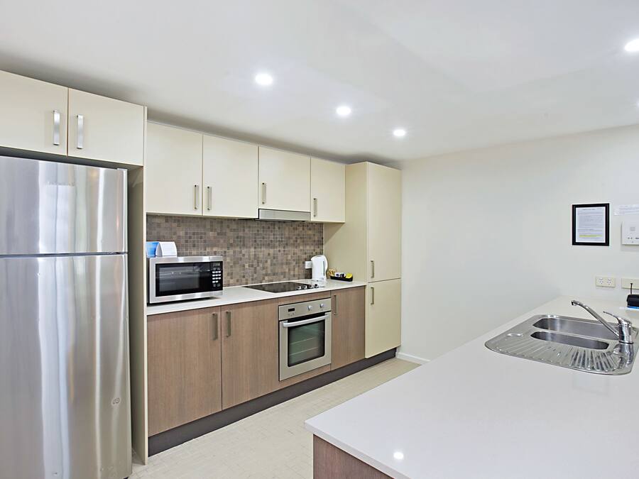 A modern kitchen with stainless steel appliances, wooden cabinets, and a white countertop.