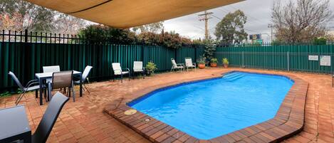 Een buitenzwembad, ligstoelen bij het zwembad