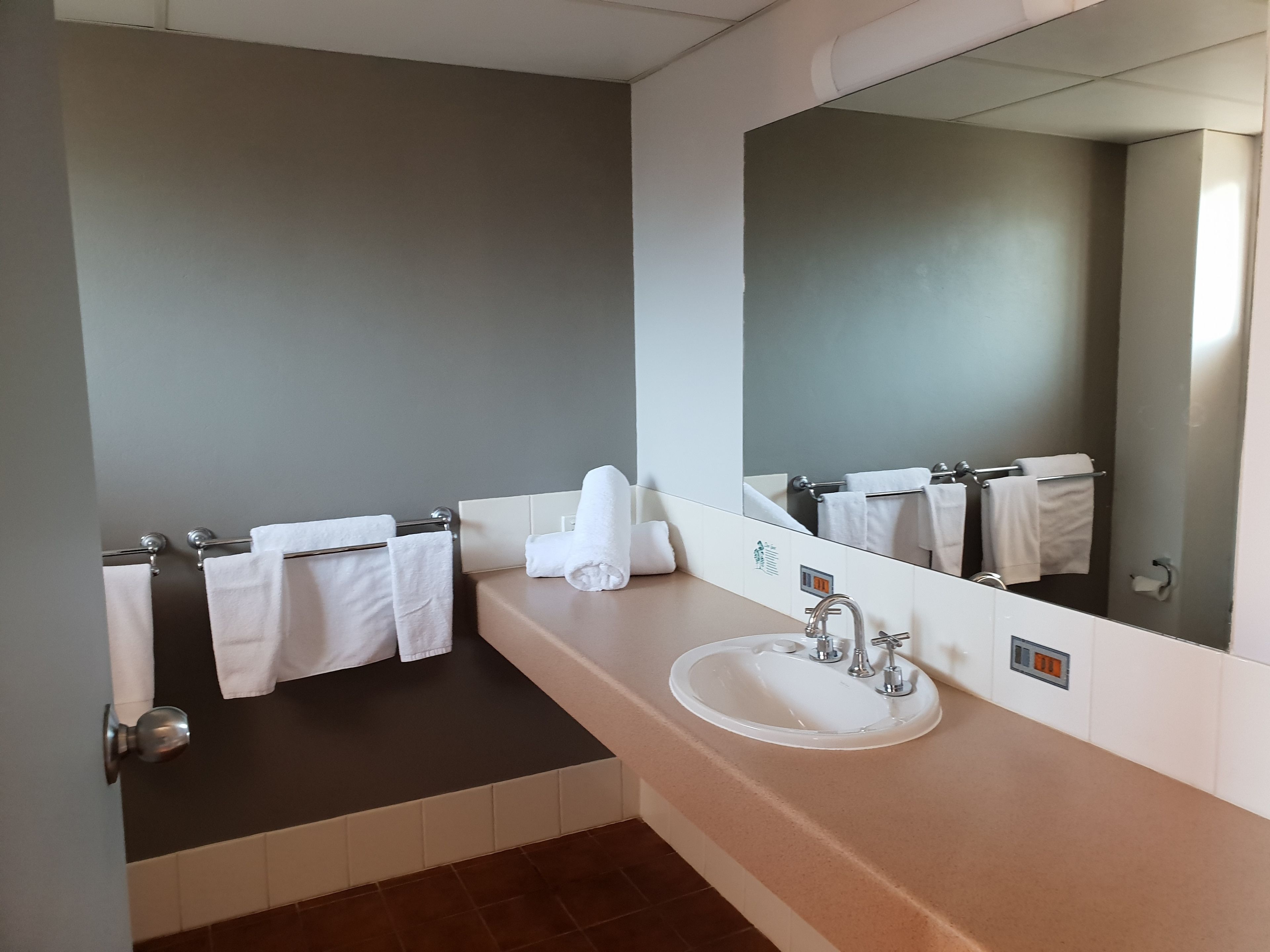 Un baño moderno con un espejo grande, un lavamanos y dos barras para toallas.