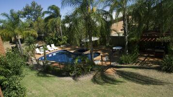 A backyard with a swimming pool, palm trees, and a brick wall.