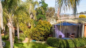 A private garden with a glass-enclosed patio, lush greenery, and a swimming pool. - Crystal Fountain Motel Albury (Lavington)