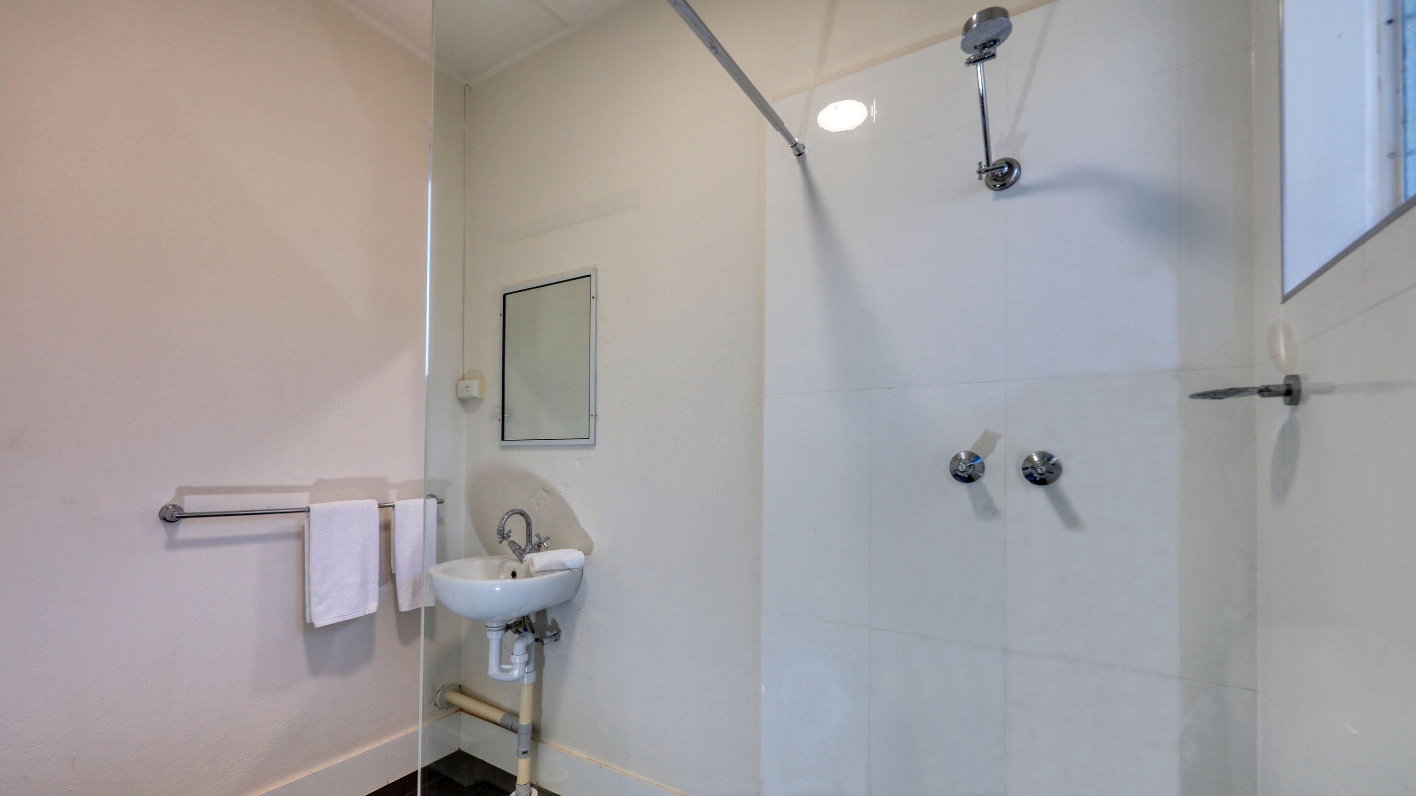 Un baño moderno con cabina de ducha de vidrio, un lavabo y un espejo.