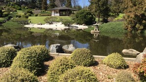 A traditional Japanese garden with a pond, rock formations, and a pavilion.