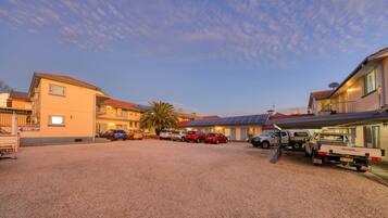 A hotel with multiple floors, solar panels on the roof, and a gravel parking area.