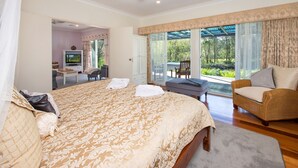 Een slaapkamer met een groot bed, een stoel, een bureau en uitzicht op de omgeving.