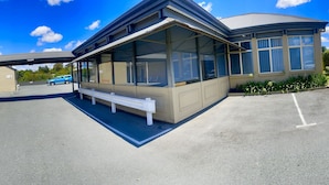 Un motel doté d’un parking couvert, d’un petit espace salon et d’un bâtiment avec de grandes fenêtres.