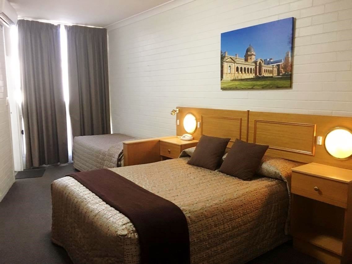 Une chambre d’hôtel avec un grand lit, deux tables de chevet avec des lampes, un tableau au mur et une fenêtre avec des rideaux.