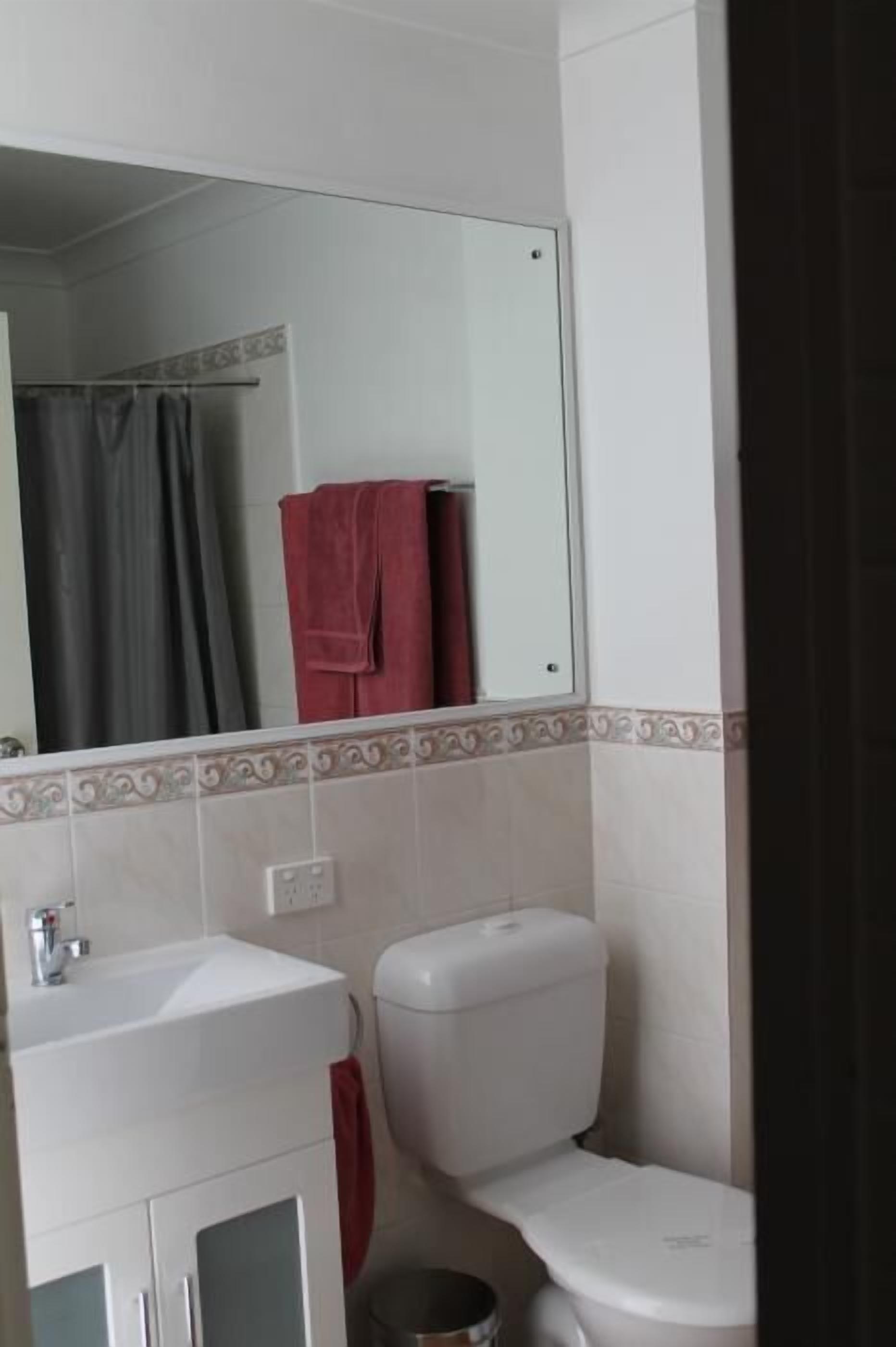 Een badkamer met een wit wastafel, toilet en spiegel.