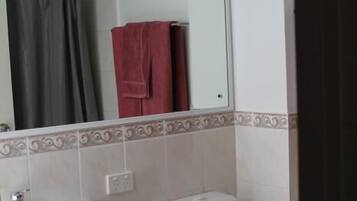 Een badkamer met een wit wastafel, toilet en spiegel.