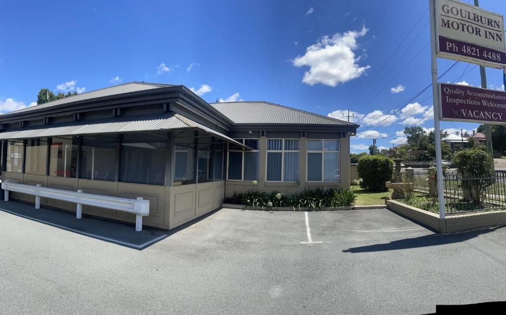 A motor inn with a covered waiting area, a bench, and a clear sky.