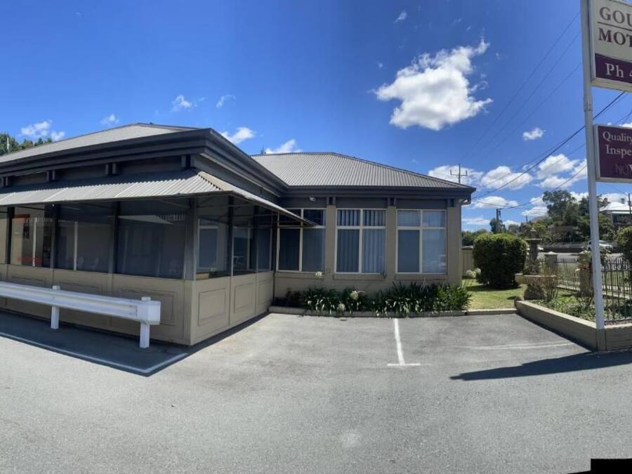 A motor inn with a covered waiting area, a bench, and a clear sky.