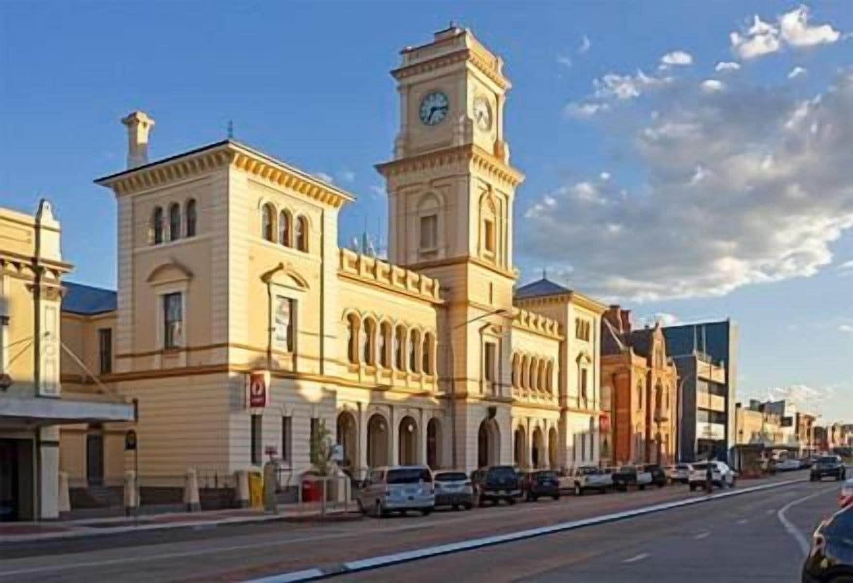 A historic building with a clock tower, a main entrance, and a street in front.
