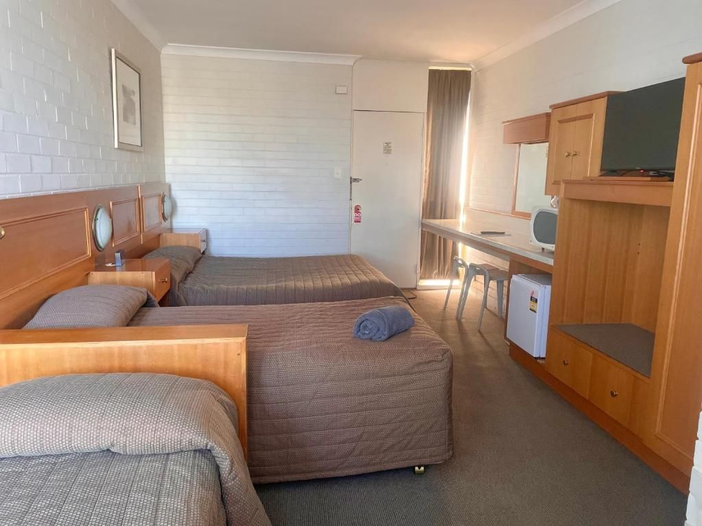A hotel room with two beds, a desk, a television, and a wardrobe.