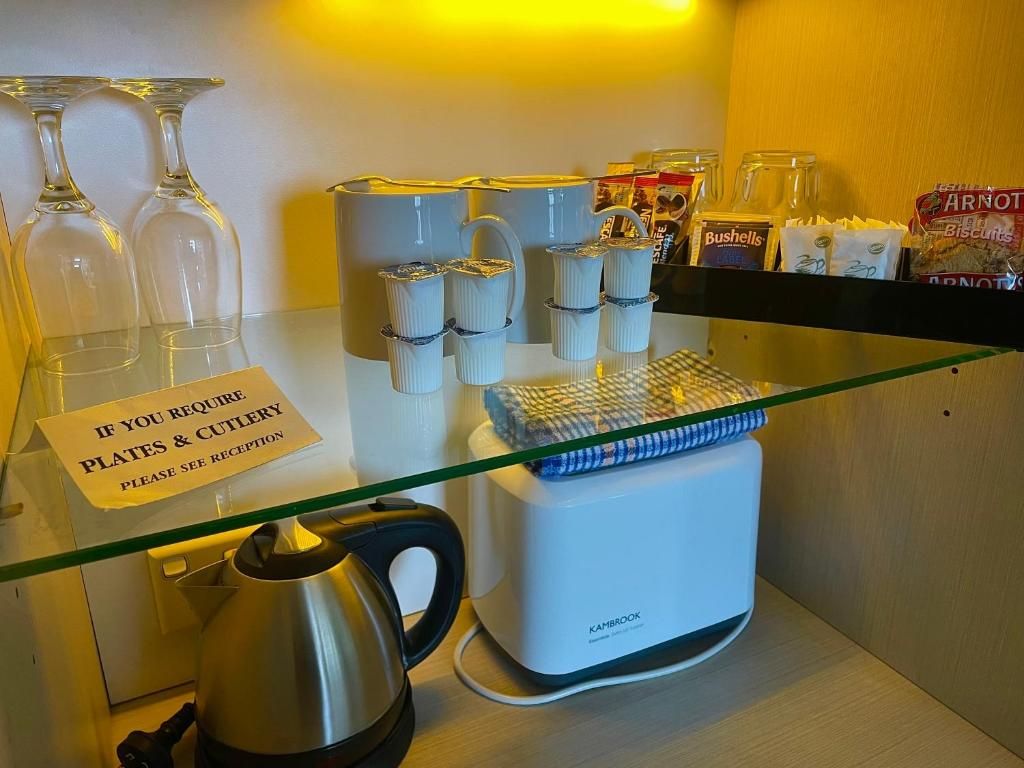 Un espace d’accueil d’hôtel avec une vitrine en verre contenant des assiettes, des couverts et une bouilloire.