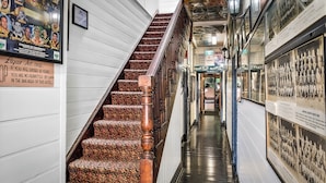 A hallway with a wooden staircase, framed pictures on the walls, and a sign about the Liquor Act of 1982.