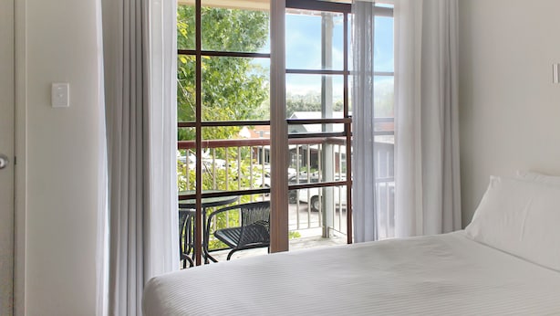 A bedroom with a large window, a bed, and a view of the outside.