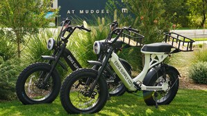 Dos bicicletas estacionadas frente a un letrero que dice 'THE CUDDLE AT MUDGE'.